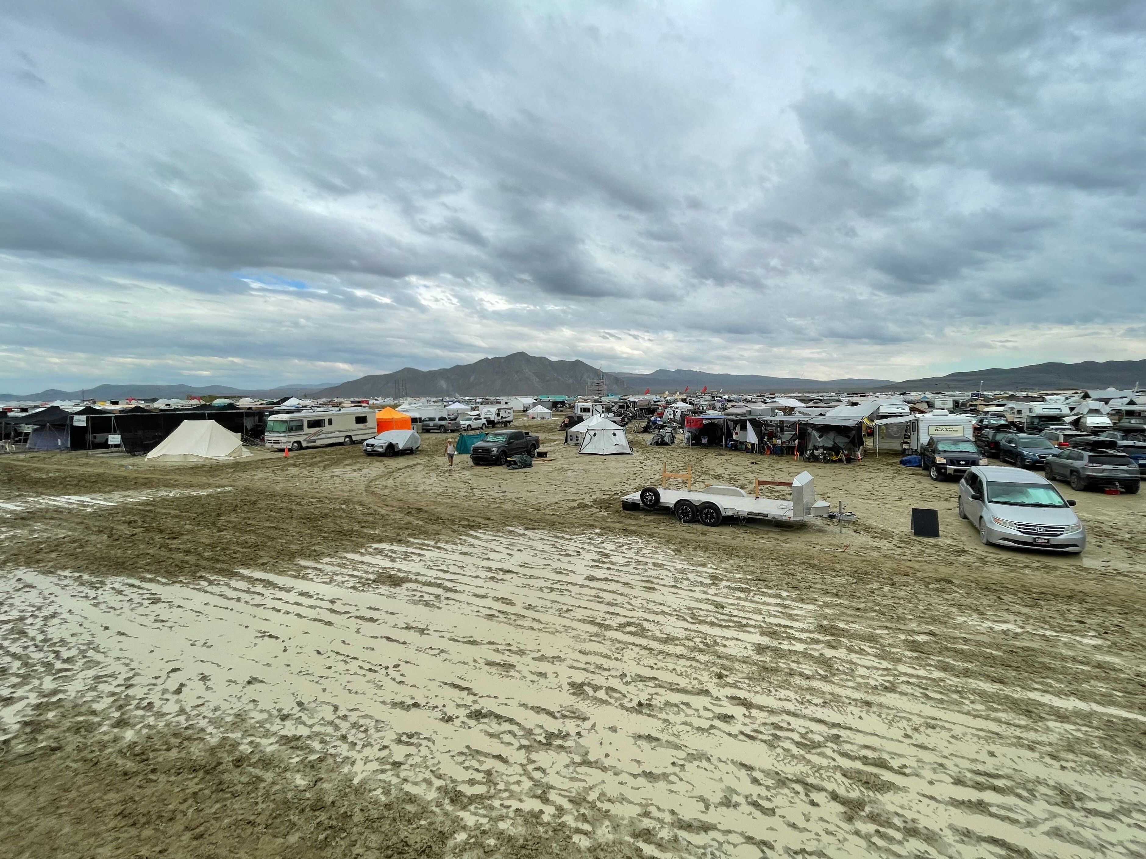 caption: Camps are set on a muddy desert plain on September 2, 2023, after heavy rains turned the annual Burning Man festival site in Nevada's Black Rock desert into a mud pit.