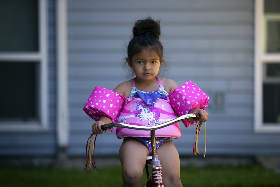 caption: Vay, 5, rides a bicycle outside of the apartment complex where she lives on Friday, July 15, 2022.