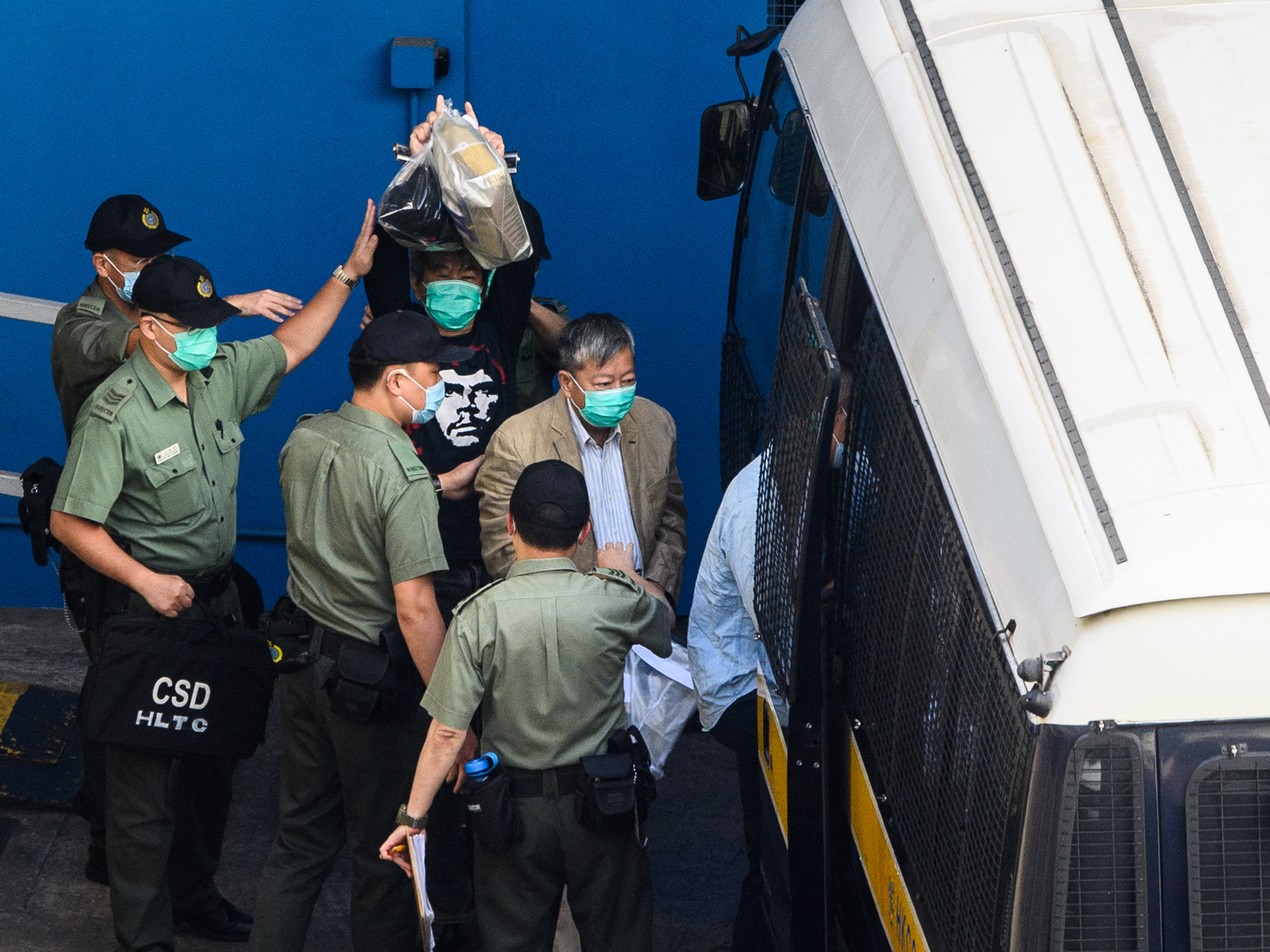 caption: Pro-democracy activists Leung Kwok-hung, center, and Lee Cheuk-yan walk to a Hong Kong Correctional Services van Friday before being driven to their sentencing hearing. Both received three years in prison on for organizing and attending an authorized protest on China's National Day on October 1, 2019.