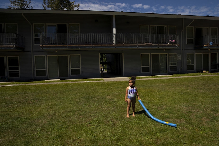 caption: Vay, 5, holds a pool noodle outside of her family’s apartment as they meet with their case manager, Toni Gardner, on Friday, July 15, 2022. 