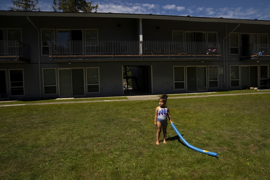 caption: Vay, 5, holds a pool noodle outside of her family’s apartment as they meet with their case manager, Toni Gardner, on Friday, July 15, 2022.