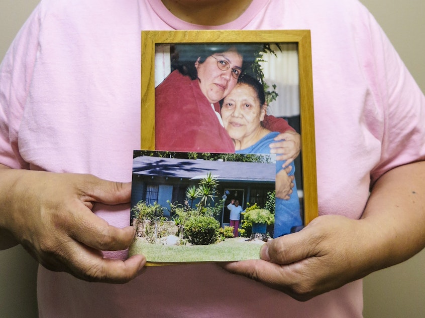 caption: Maria Rivas holds photographs of her mother, Julia Medina, who died in 2012. Maria cared for Julia for six years at the end of her life.