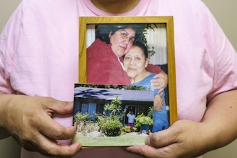 caption: Maria Rivas holds photographs of her mother, Julia Medina, who died in 2012. Maria cared for Julia for six years at the end of her life.