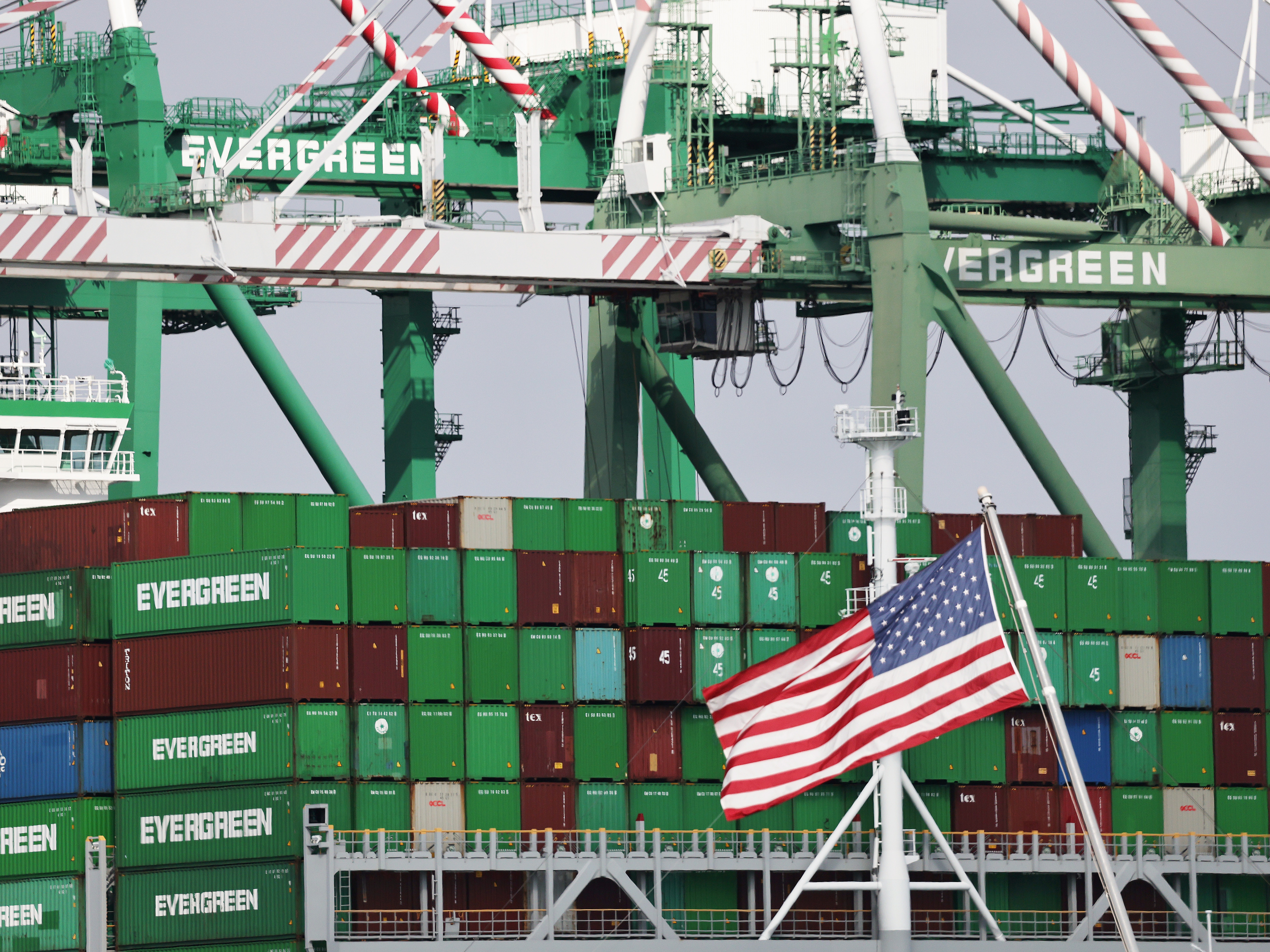 caption: An American flag flies near shipping containers at the Port of Los Angeles on Sept. 26.