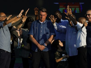 caption: Brazilian President Jair Bolsonaro receives a blessing during a music festival organized by a local evangelic radio station on July 2, in Rio de Janeiro.