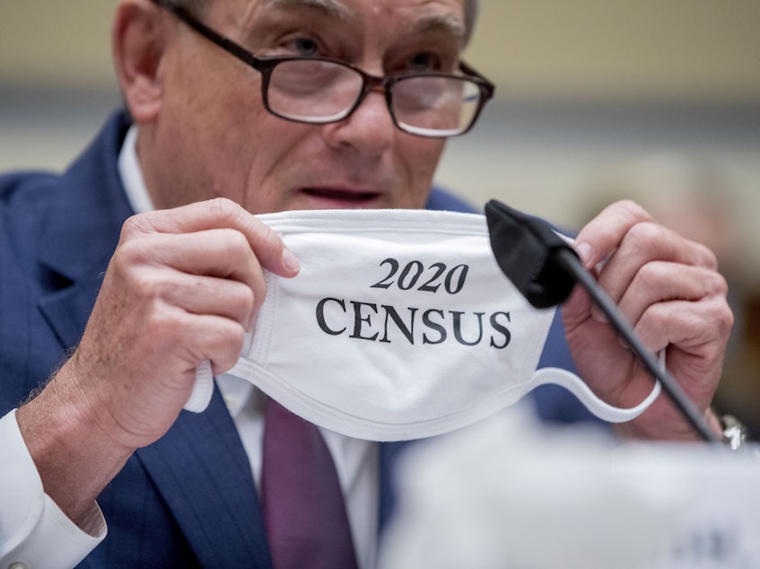 caption: Census Bureau Director Steven Dillingham holds up his mask with the words "2020 Census" as he testifies before a House Committee on Oversight and Reform hearing on the census in July.