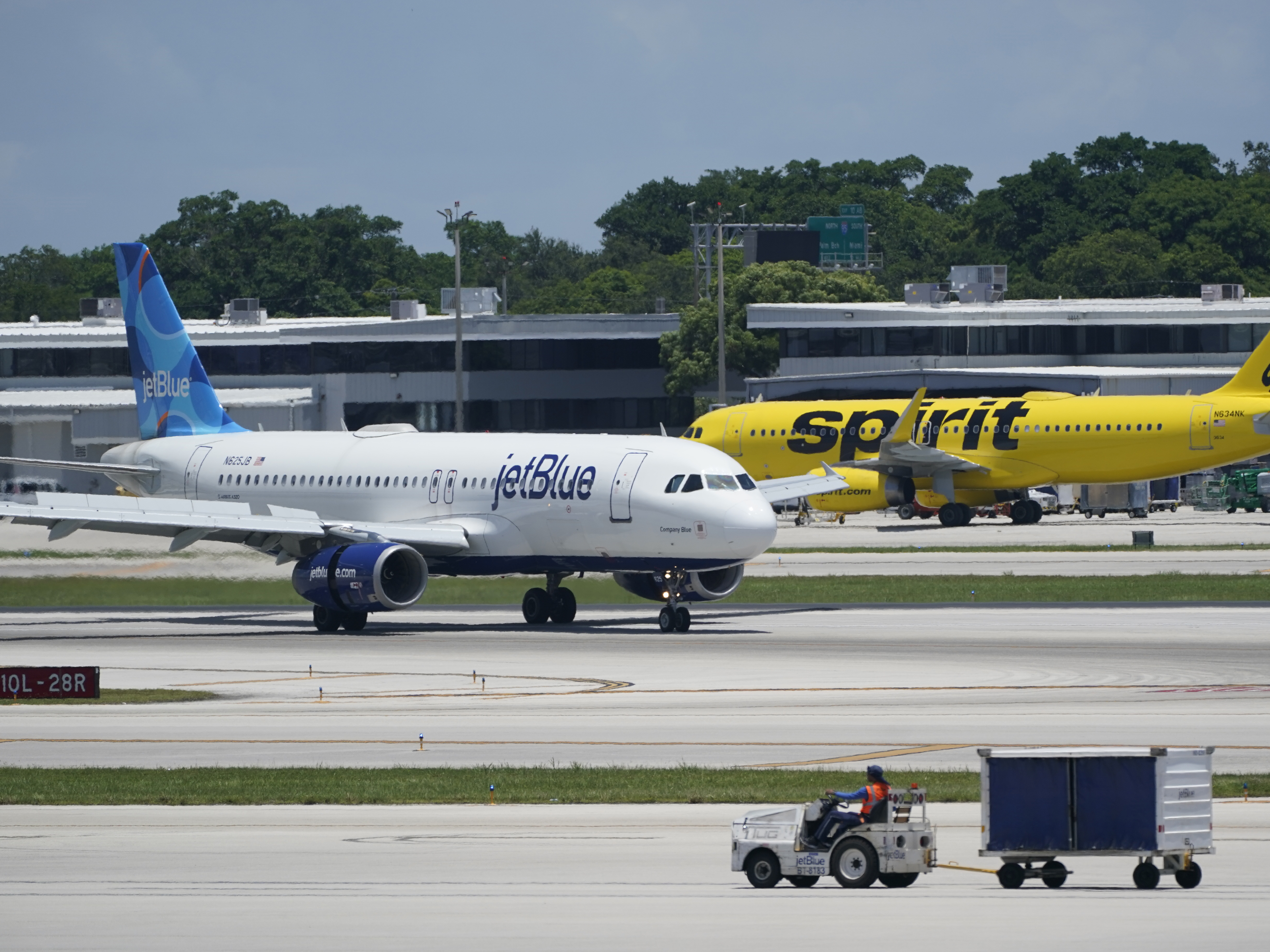 caption: A JetBlue Airways Airbus A320 (left) passes a Spirit Airlines Airbus A320 as it taxis on the runway on July 7, 2022, at the Fort Lauderdale-Hollywood International Airport in Fort Lauderdale, Fla. The Biden administration wants to block JetBlue from buying Spirit, saying the deal would reduce competition and hurt travelers.