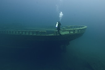 caption: A diver explores Grecian shipwreck at Thunder Bay National Marine Sanctuary.