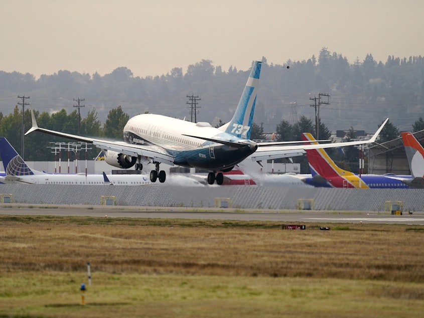 caption: A Boeing 737 Max jet, piloted by Federal Aviation Administration chief Steve Dickson, flies past parked Boeing jets as it prepares to land at Boeing Field following a test flight in September.