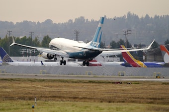 caption: A Boeing 737 Max jet, piloted by Federal Aviation Administration chief Steve Dickson, flies past parked Boeing jets as it prepares to land at Boeing Field following a test flight in September.