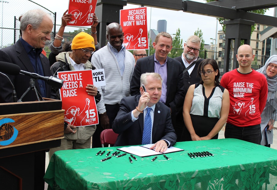 caption: A day after it received final approval in City Council, Seattle Mayor Ed Murray signs the new $15 an hour minimum wage law