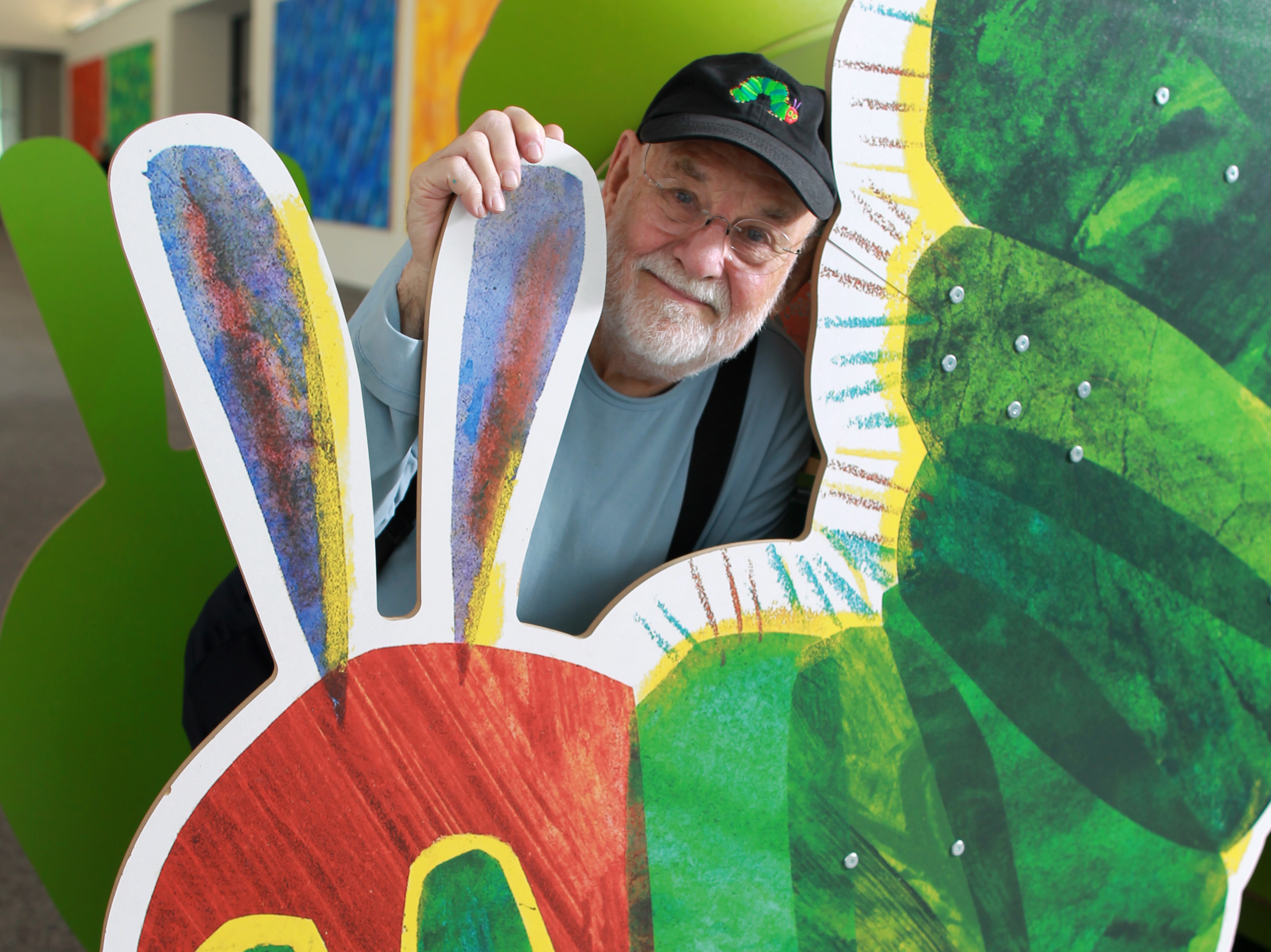 caption: Eric Carle with a cutout of his famously hungry caterpillar at the Eric Carle Museum of Picture Book Art in Amherst, Mass.