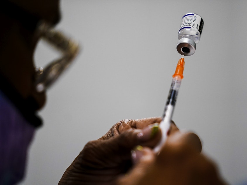 caption: A syringe is prepared with the Pfizer COVID-19 vaccine at a vaccination clinic in Chester, Pa., on Dec. 15, 2021. Pfizer says tweaking its COVID-19 vaccine to better target the omicron variant is safe and boosts protection.