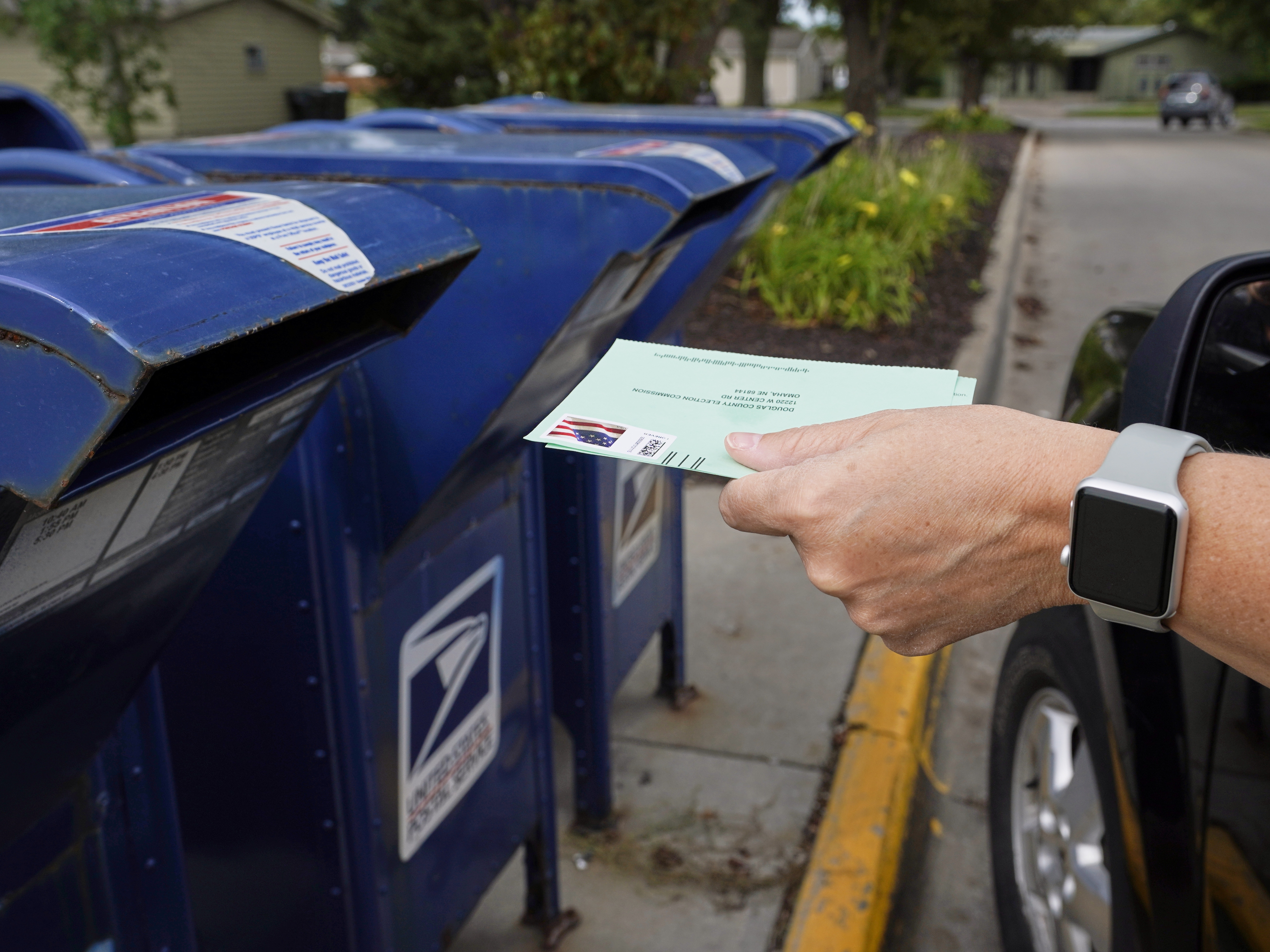caption: A person drops applications for mail-in-ballots into a mailbox in 2020 in Omaha, Neb.