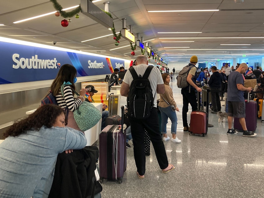 caption: Travelers wait at a Southwest Airlines baggage counter after flight cancellations hit Los Angeles International Airport on Monday. The airline warns it will fly about one-third of its schedule for the next several days.