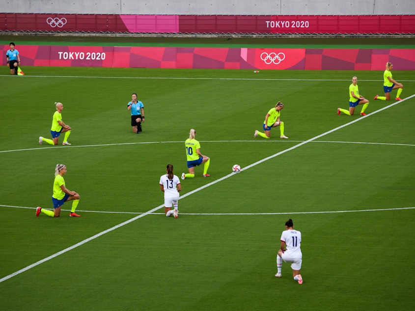 caption: Players and officials take a knee just before the start of Wednesday's match between the U.S and Swedish women's soccer teams.