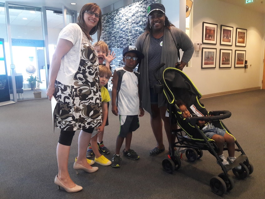 caption: Tricia Schroeder, Lashondra Hayes, and their children. Hayes works as a nanny for Schroeder.