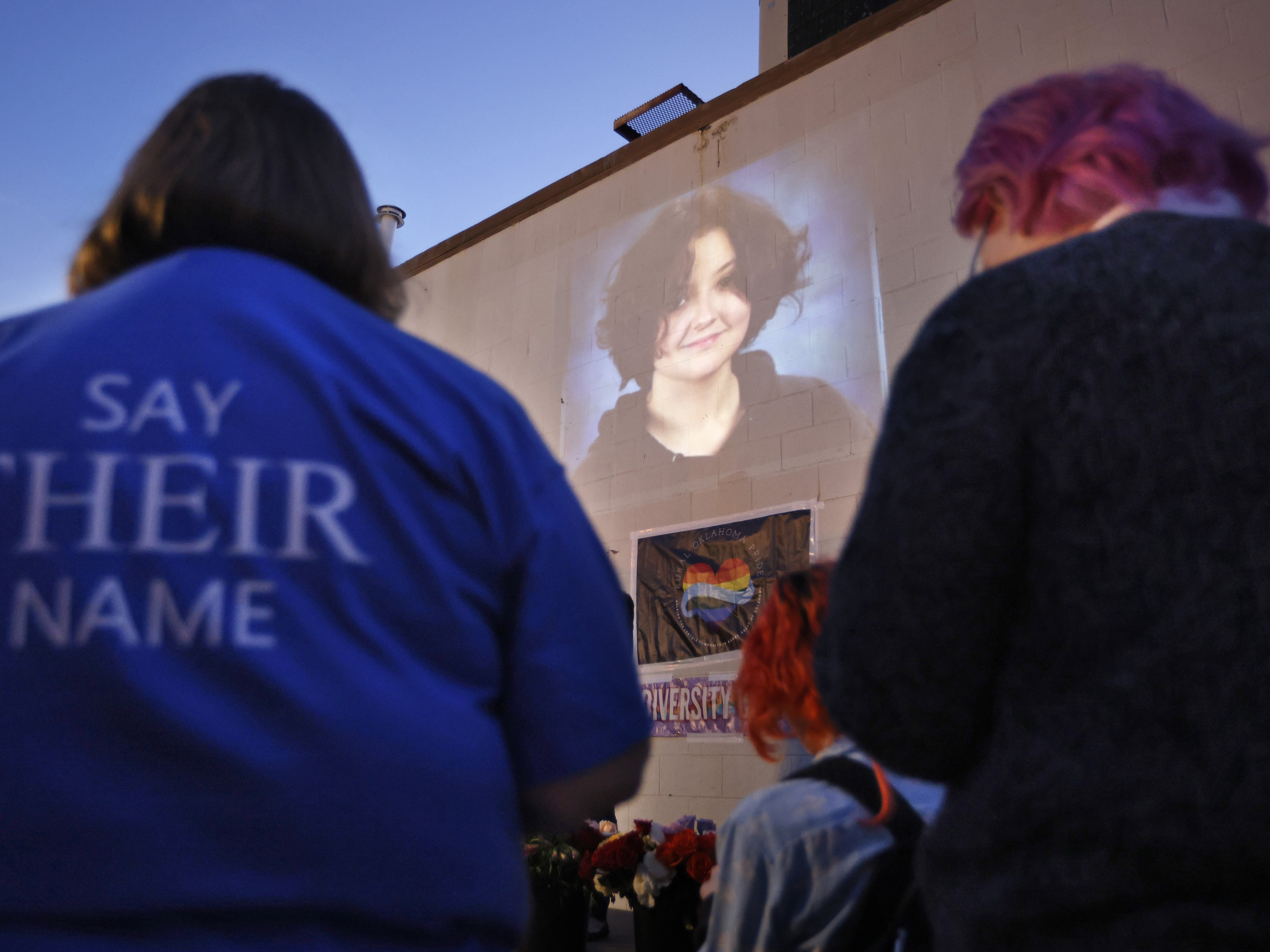 caption: A photograph of Nex Benedict, a nonbinary teenager who died one day after a fight in a high school bathroom, is projected during a candlelight service at Point A Gallery, Saturday, Feb. 24, 2024, in Oklahoma City.