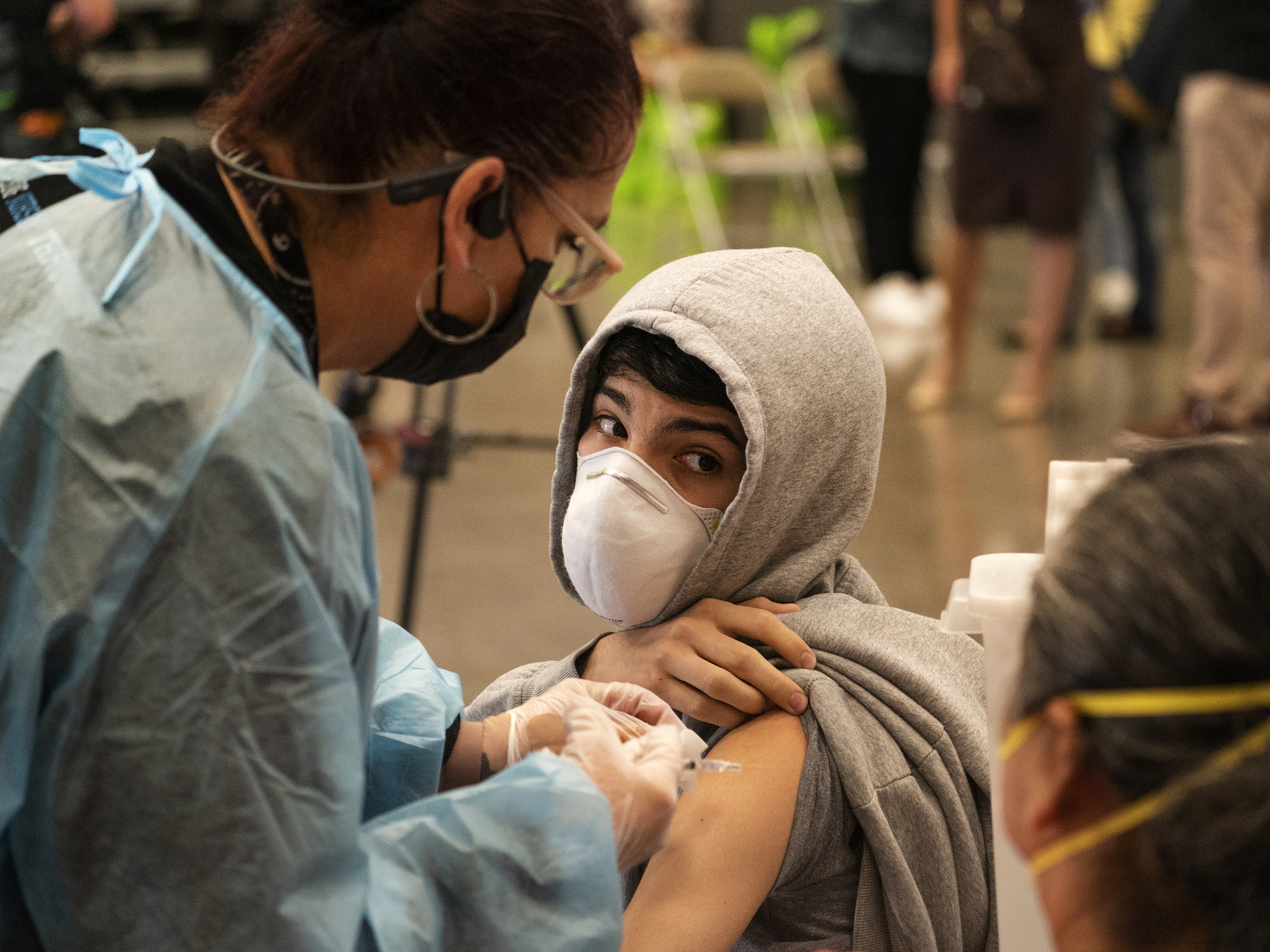 caption: A student looks back at his mother, as he is vaccinated at a school-based COVID-19 vaccination clinic for students 12 and older in San Pedro, Calif., last month.