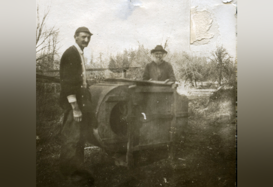 caption: Black pioneer George Bush's grandson, left, and son, right, stand next to a fanning mill on the family's farm near present day Tumwater, Washington. A monument to George Bush and his family is planned for Washington's Capitol Campus.
