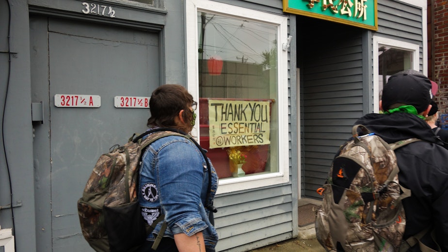 caption: Protestors departing the June 12th silent march pass the Seattle branch of the Lee Family Association on Beacon Hill. The organization, established in San Francisco in 1866, purchased the storefront in 2014 to serve as a cultural center and social space. Like all other community centers in the city, the Lee Family Association will remain closed until phase three of the lockdown, at which point most businesses and gathering places can open at reduced capacity.