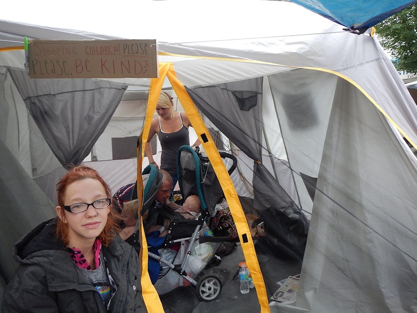 caption: Jackie O'Bryan in front of her family's tent at a University District homeless camp earlier this year.