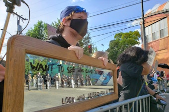 caption: "Want to see who came to riot?" asks a mirror held by a protester in Capitol Hill. "Look who dressed for a riot." Protests continue across Seattle in the wake of the police killings of George Floyd and scores of other Black people over the years.