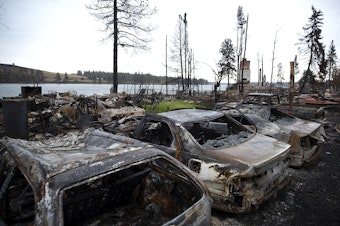 caption: Homes and vehicles destroyed by the Gray Fire are shown on Sunday, September 3, 2023, along the west side of Silver Lake in Spokane County. Over 10,000 acres and 240 homes burned in the fire. 