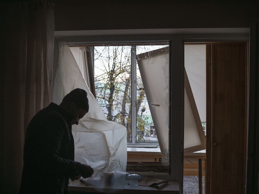 caption: A man uses plastic to cover a broken window in his apartment following a Russian drone attack in Kyiv, Ukraine, on Nov. 25.