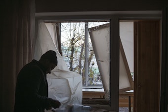 caption: A man uses plastic to cover a broken window in his apartment following a Russian drone attack in Kyiv, Ukraine, on Nov. 25.