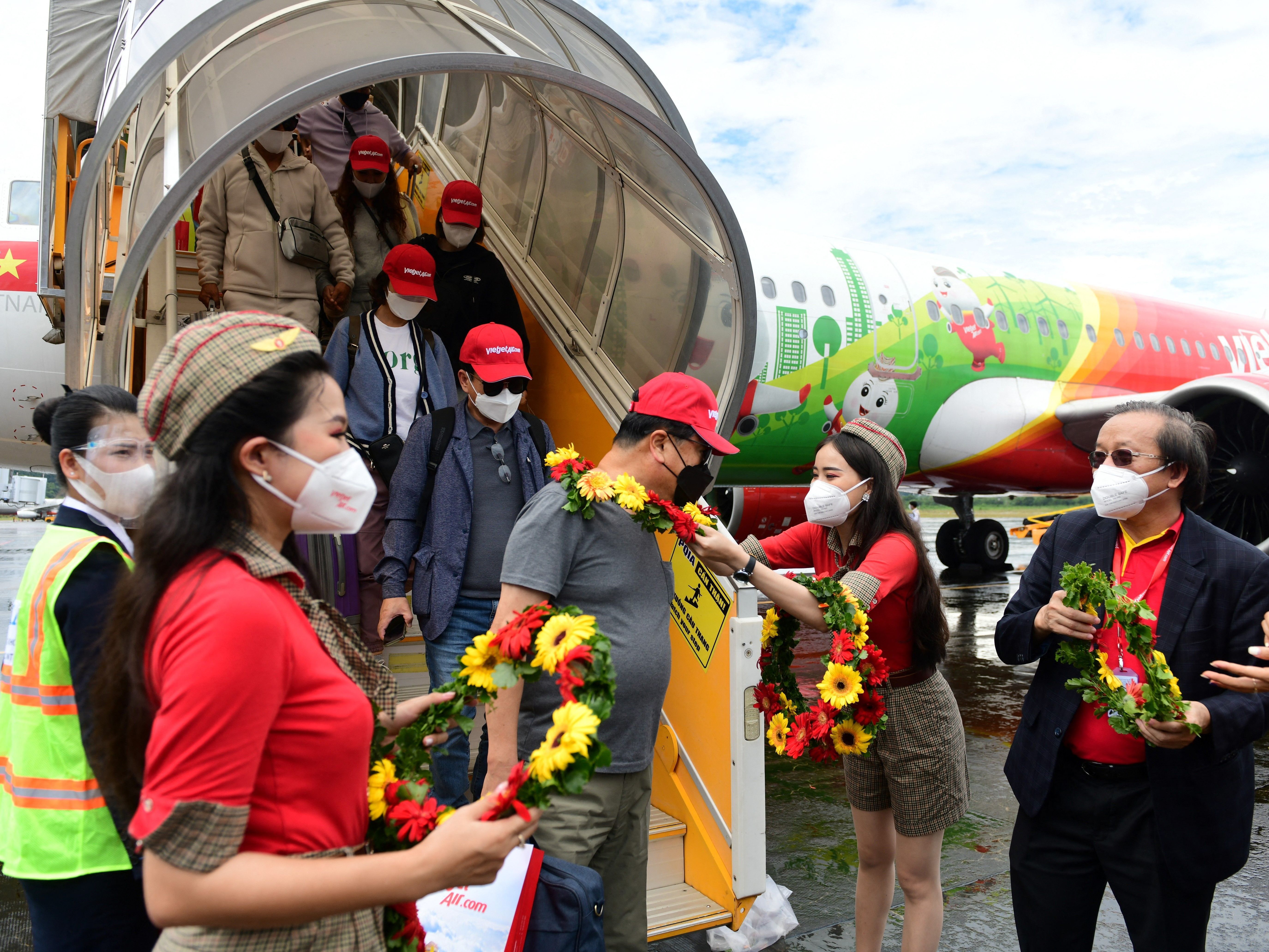 caption: Arriving South Korean tourists receive flower garlands at Phu Quoc international airport on November 20, 2021, as the island welcomes its first international tourists to arrive after a Covid-19 coronavirus vaccine passport scheme kicked off this month in Vietnam.