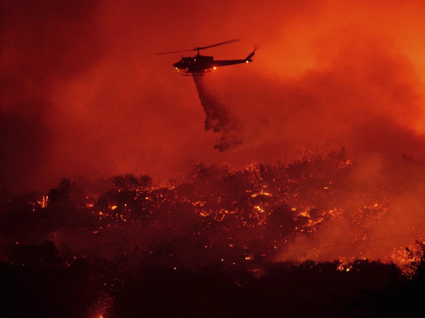caption: A helicopter drops water on the Cave Fire burning in the Los Padres National Forest above Santa Barbara, Calif., on Tuesday.