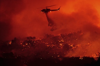 caption: A helicopter drops water on the Cave Fire burning in the Los Padres National Forest above Santa Barbara, Calif., on Tuesday.