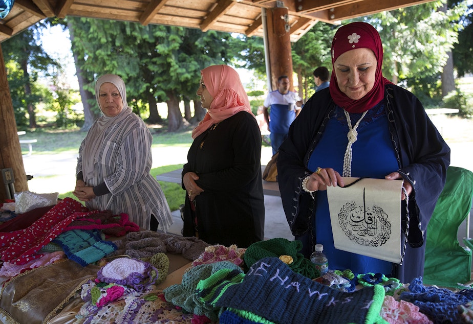 caption: Suham Albayati, right, originally from Baghdad, arranges items on her table at the Kent East Hill Farmer's Market on Friday, June 30, 2017, at Morrill Meadows Park in Kent. Tap photo for slideshow.