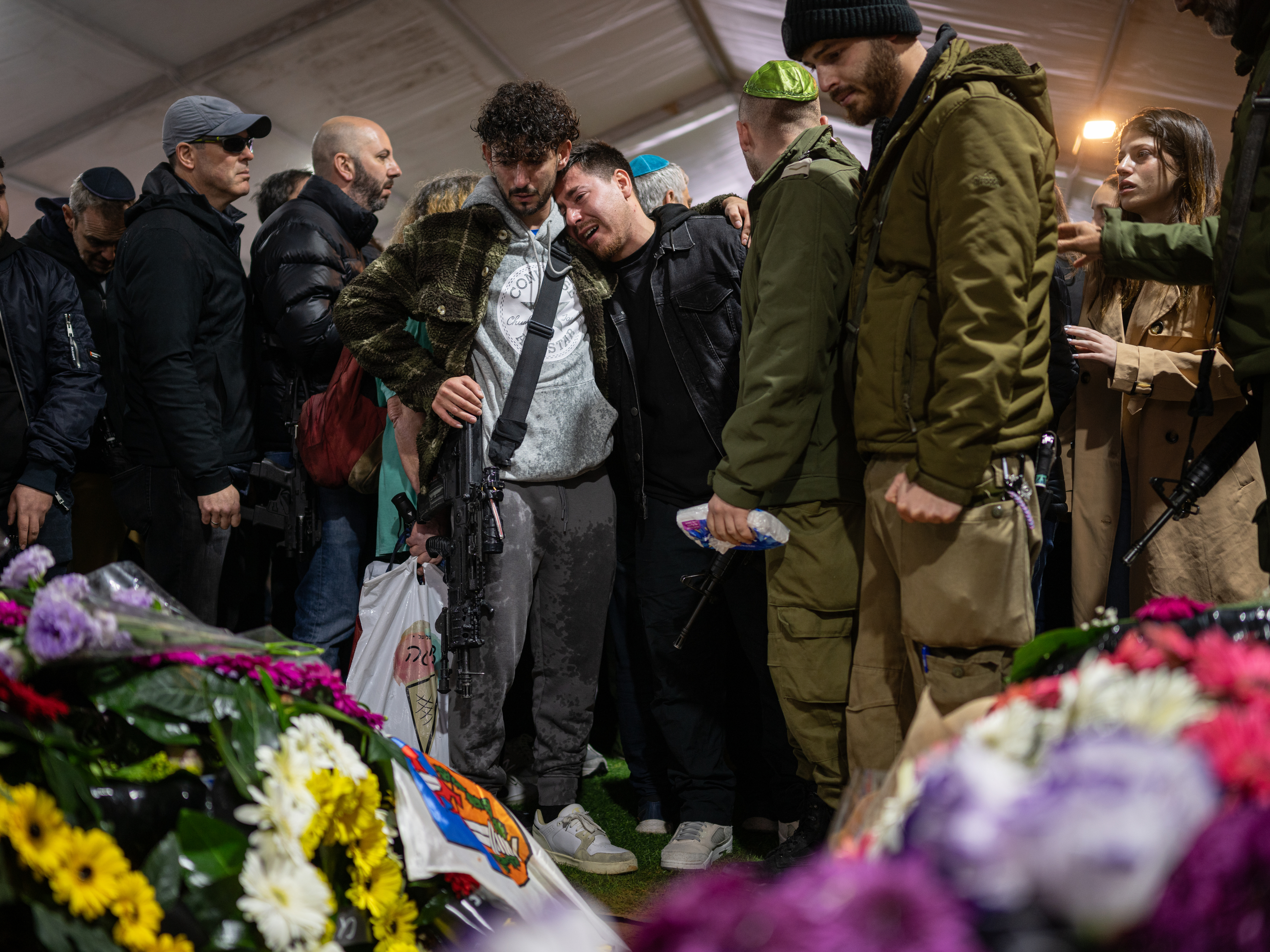 caption: Family and friends of Israeli reservist Hadar Kapeluk, who was killed in combat in Gaza, mourn at his grave during his funeral at the Mount Herzl military cemetery in Jerusalem, Israel, on Tuesday.