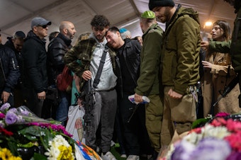 caption: Family and friends of Israeli reservist Hadar Kapeluk, who was killed in combat in Gaza, mourn at his grave during his funeral at the Mount Herzl military cemetery in Jerusalem, Israel, on Tuesday.