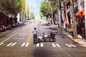 caption: A Seattle Police officer stands by ahead of a sanctioned parade for immigration rights.