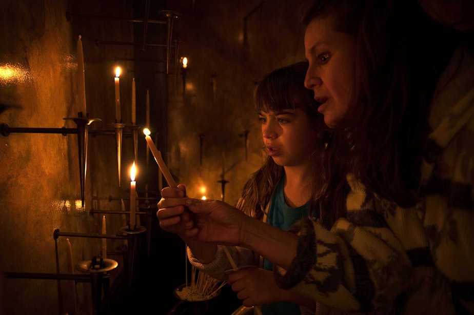 caption: Mariela Mahoney-Armas, 9, left, and Anni Armas light candles on Thursday, June 21, 2018, during a prayer and procession for families at the border at St. James Cathedral in Seattle.