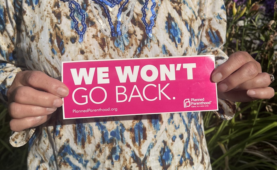 caption: Elaine Fichter holds a bumper sticker from the reproductive healthcare organization Planned Parenthood bearing the slogan “We won’t go back” on July 28, 2023 in Concrete, WA. This phrase has become a rallying cry for the pro-choice movement. 