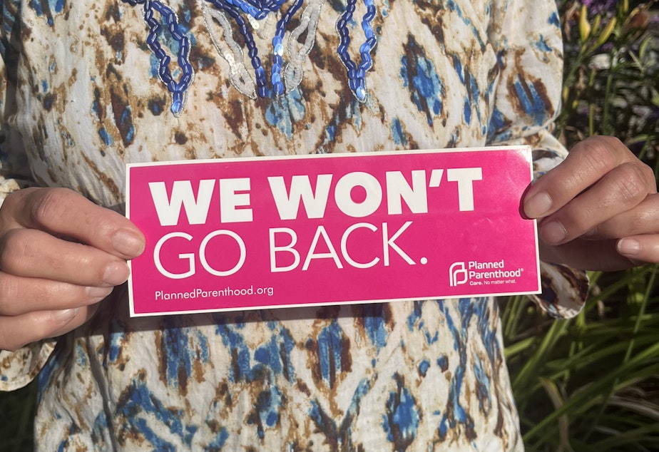 caption: Elaine Fichter holds a bumper sticker from the reproductive healthcare organization Planned Parenthood bearing the slogan “We won’t go back” on July 28, 2023 in Concrete, WA. This phrase has become a rallying cry for the pro-choice movement. 