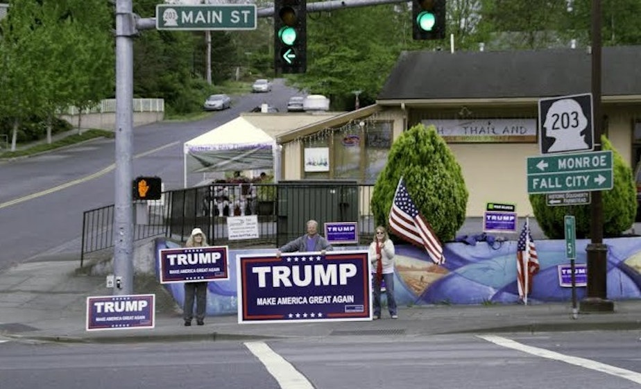 caption: Debbi LerMond and other Trump supporters wave signs at an intersection in Duvall.  She says so many people flip them off that she calls this "bird-watching."