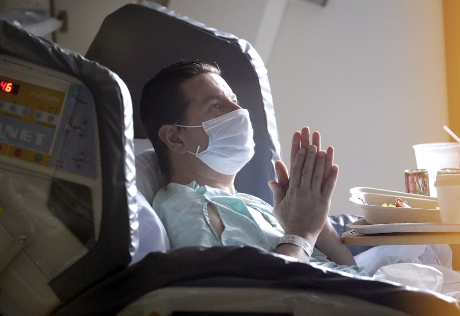 caption: Kevin Barrett, in quarantine after his former hospital roommate tested positive for COVID-19, rubs his hands together as he recovers from an injury in the acute care unit of Harborview Medical Center, Friday, Jan. 14, 2022, in Seattle.