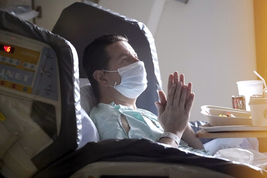 caption: Kevin Barrett, in quarantine after his former hospital roommate tested positive for COVID-19, rubs his hands together as he recovers from an injury in the acute care unit of Harborview Medical Center, Friday, Jan. 14, 2022, in Seattle. 