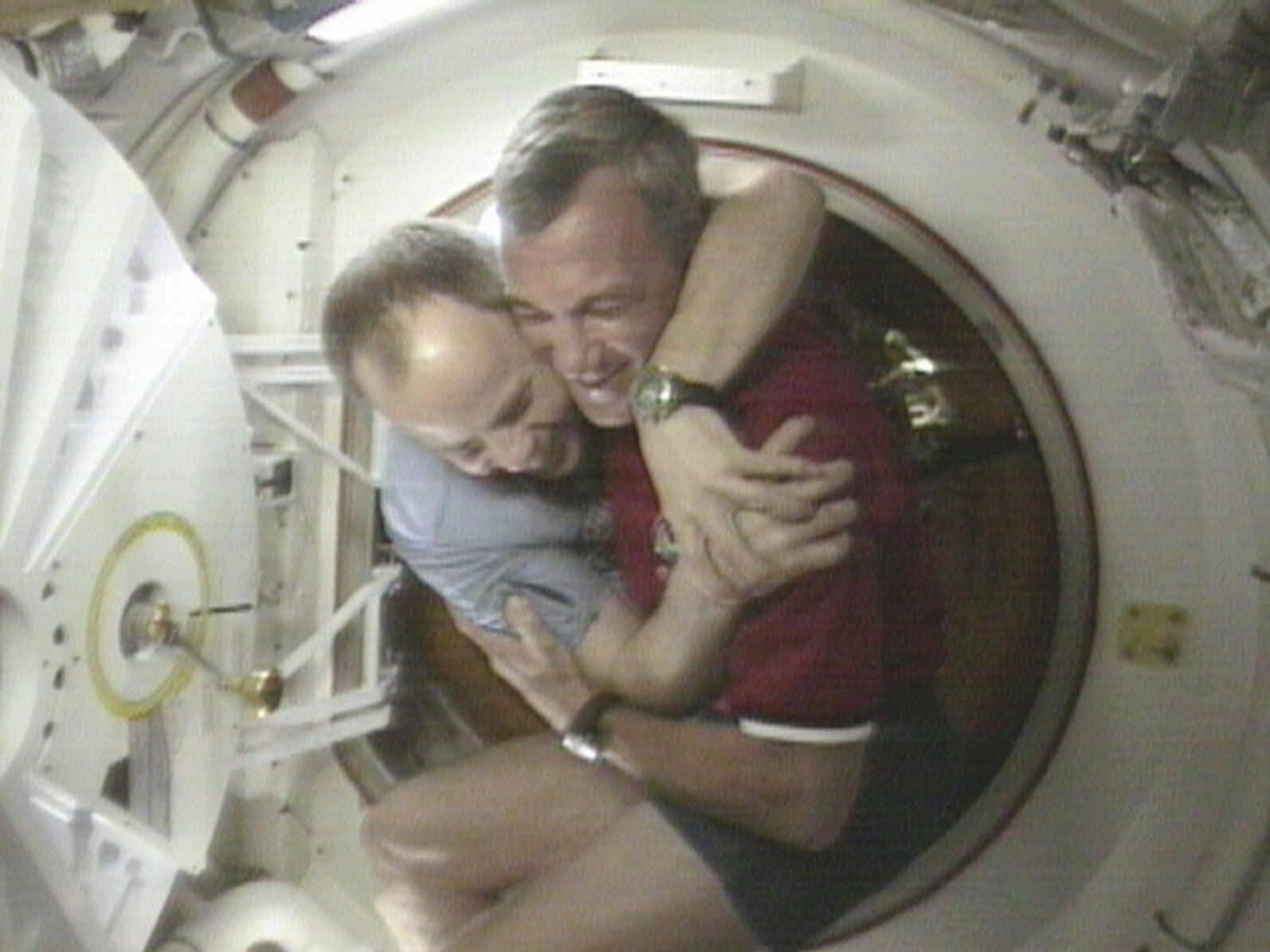 caption: U.S. Space Shuttle Commander Terrence Wilcutt (right) and Mir Commander Anatoly Solovyev hug after opening the hatches between the space shuttle Endeavour and the Russian Space station Mir Saturday, Jan. 24, 1998, in this image from television