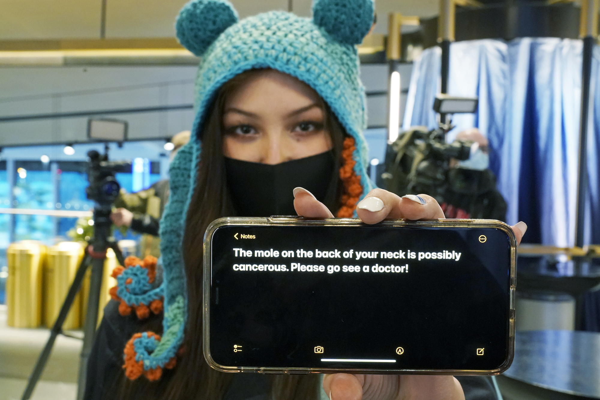 caption: Seattle Kraken fan Nadia Popovici poses for a photo before an NHL hockey game between the Kraken and the Vancouver Canucks, Saturday, Jan. 1, 2022, in Seattle. Popovici is showing the text of a message she showed to Canucks assistant equipment manager Brian "Red" Hamilton on Oct. 23, 2021, as she sat behind the Canucks' bench during the Kraken's home-opener hockey game. 