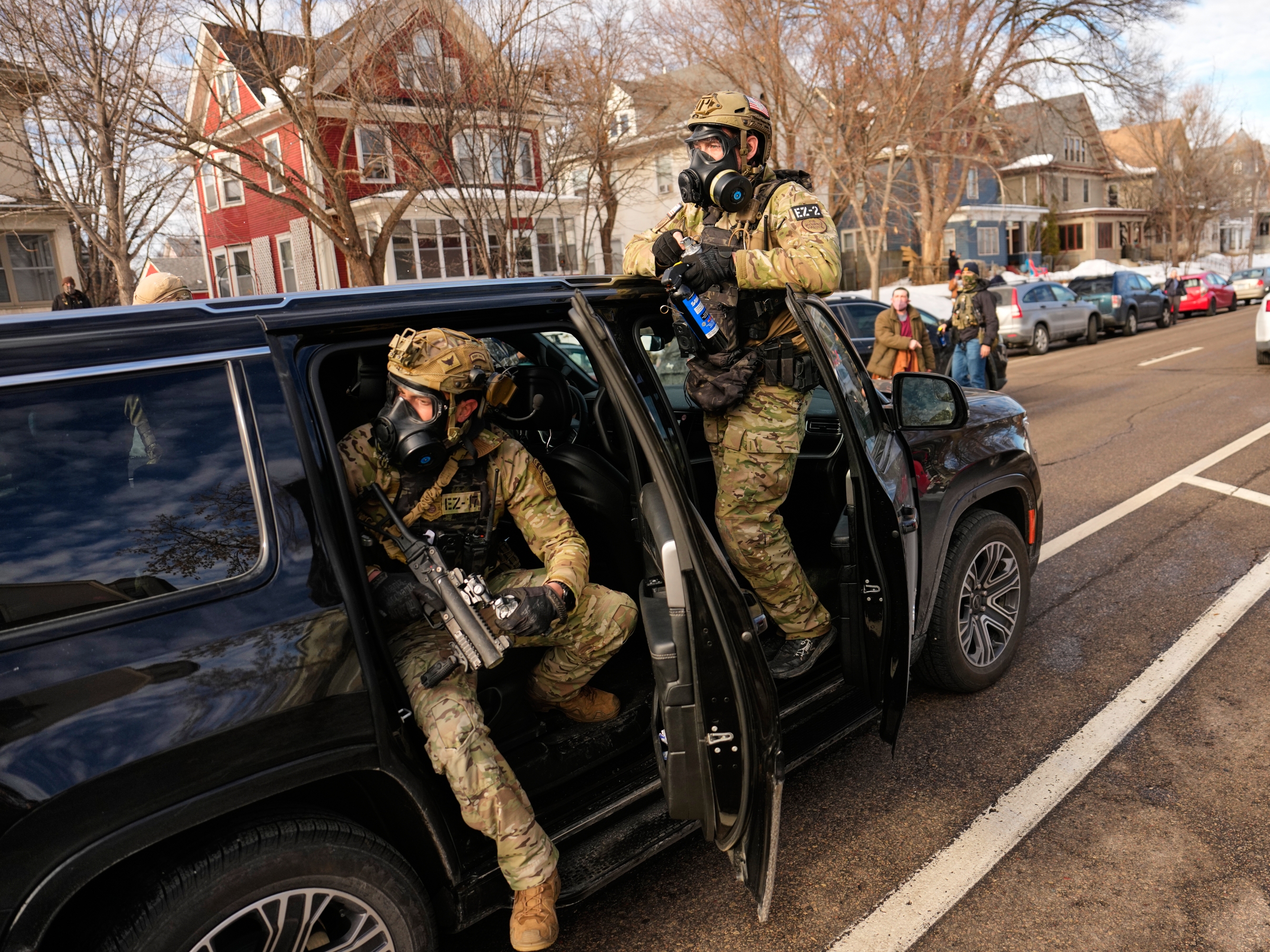 caption: Federal immigration officers get in a car as they prepare to deploy tear gas at a protest Monday in Minneapolis.