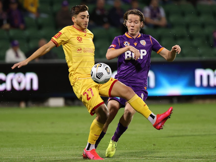 caption: Josh Cavallo of Adelaide, left, and Daniel Stynes of the Glory contest for the ball during the A-League match between Perth Glory and Adelaide United at HBF Park, on May 19 in Perth, Australia.