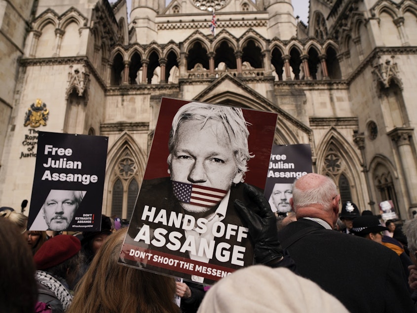 caption: A demonstrator holds a placard, after Stella Assange, wife of WikiLeaks founder Julian Assange, released a statement outside the Royal Courts of Justice, in London, Tuesday.