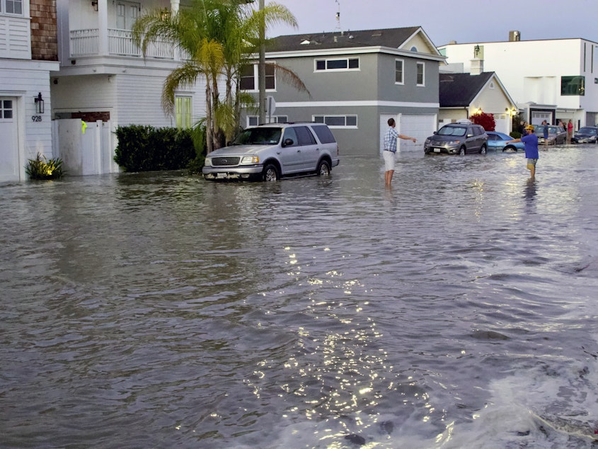 caption: Streets and homes flooded in Newport Beach, Calif., during a high tide in July 2020. So-called sunny day floods are getting more common in coastal cities and towns as sea levels rise due to climate change.