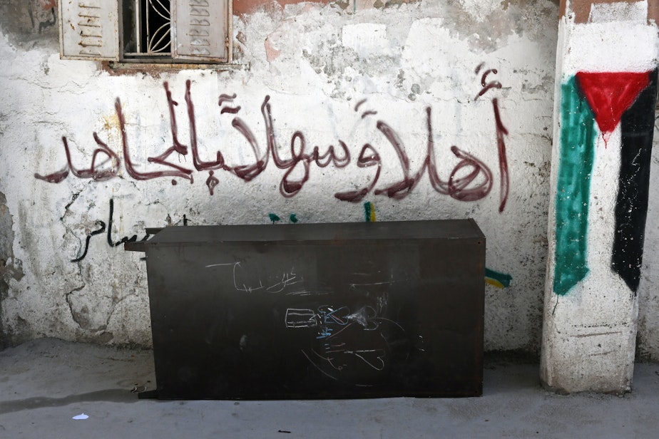 caption: Graffiti of text that says "Welcome Resistance Fighter" and a Palestinian flag in Ramallah in the West Bank.